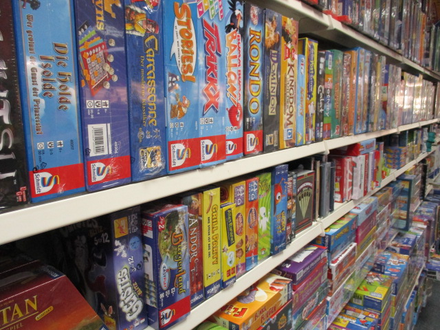 Regale voller bunter Brettspielschachteln, die nebeneinander und übereinander in einem Geschäft oder Spieleladen gestapelt sind.