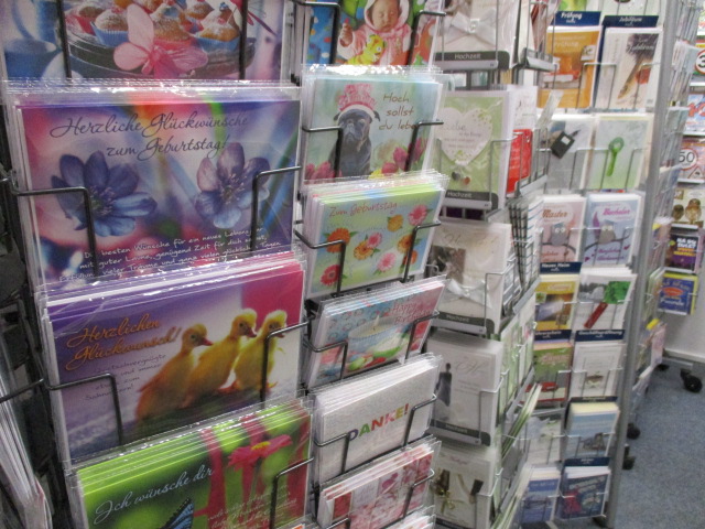 In einem Regal im Kaufhaus Heitmueller in Wennigsen sind bunte Haus&Co-Grußkarten mit deutschen Texten, Blumen, Tieren und Danksagungen in mehreren Reihen übersichtlich angeordnet.